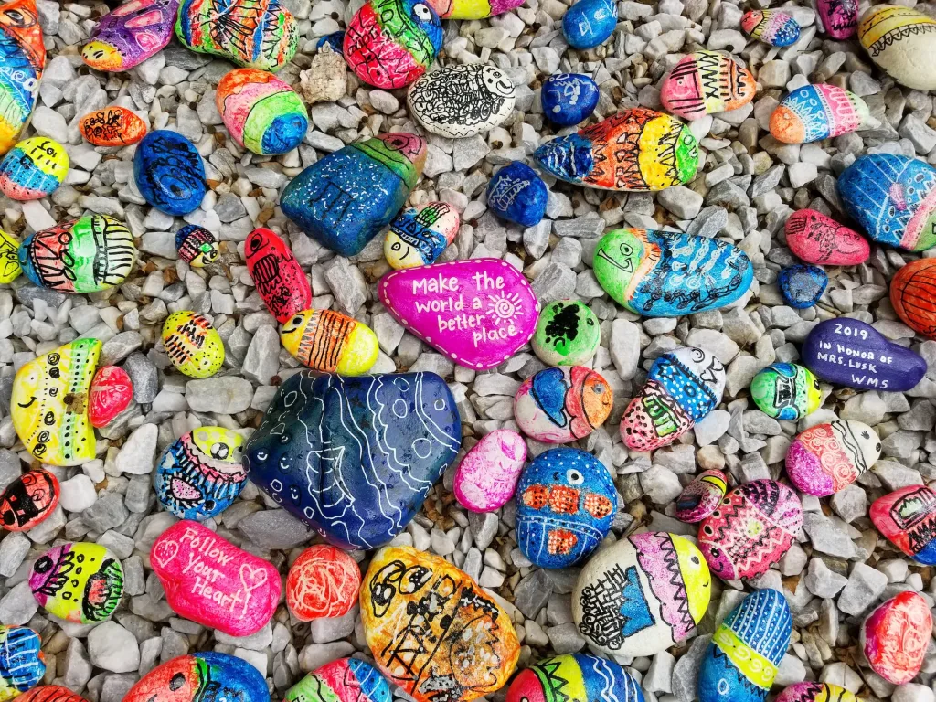 small acts of kindness and words on painted rocks on sand